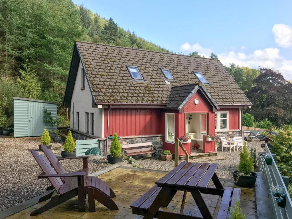 a red and white house with two benches in front of it at Dream Cottage in Strathyre