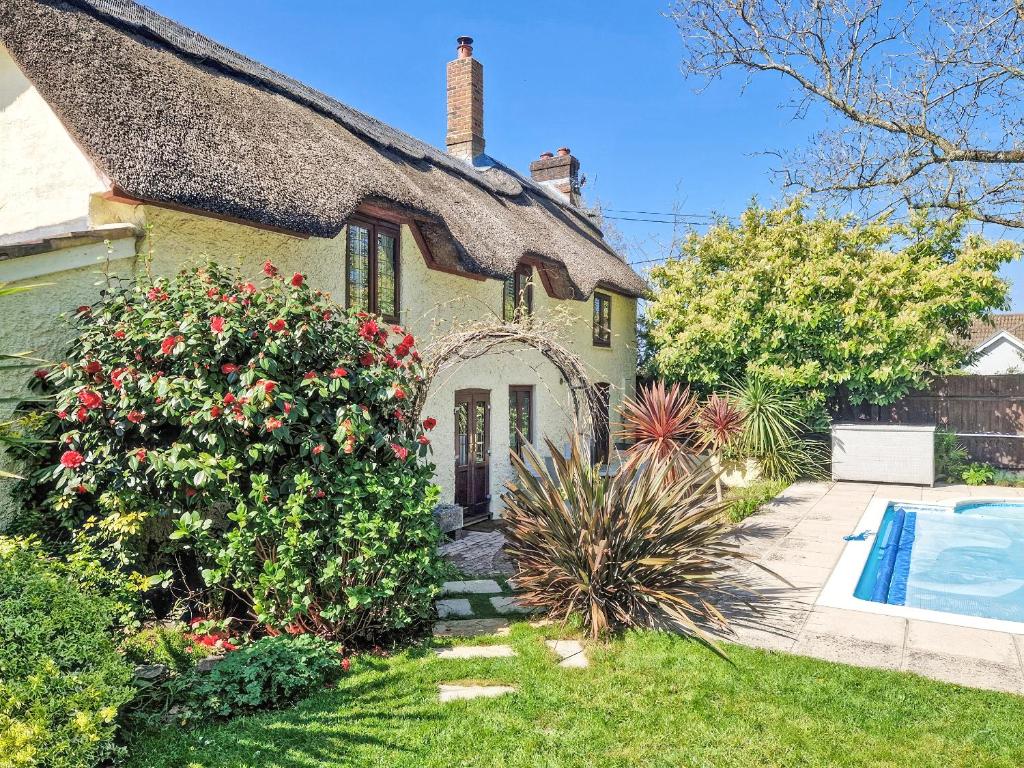 a house with a thatched roof and a swimming pool at Flanders Cottage in Lymington