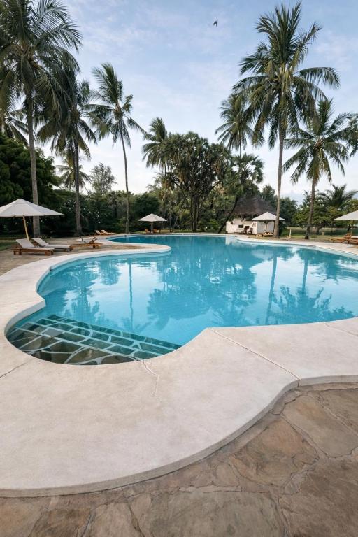 a large swimming pool with palm trees in the background at Lawford Apartment Malindi in Malindi