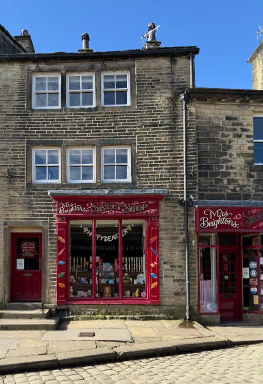a brick building with red trim on a street at Clock View - Haworth in Haworth