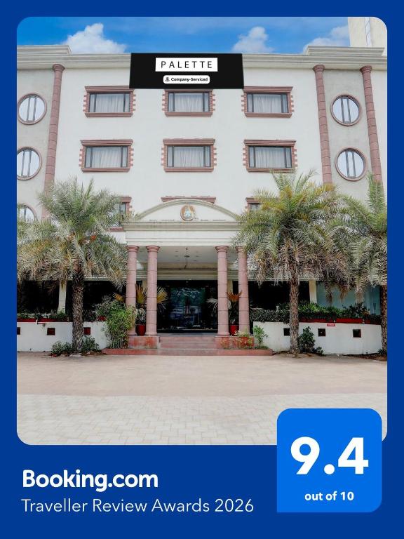a hotel with palm trees in front of it at Palette by CheckIn Anand Formerly Hotel La Casa Inn in Anand