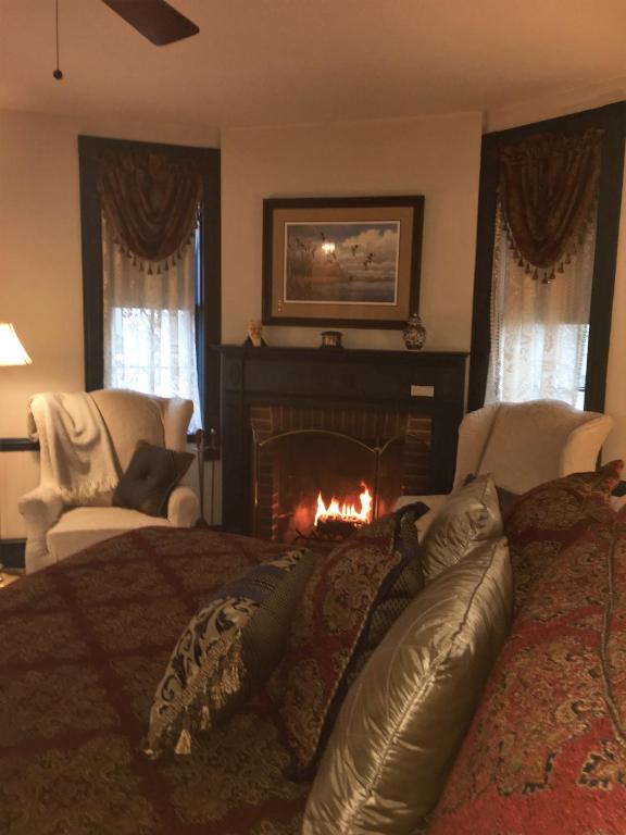 a bedroom with a bed with a fire in a fireplace at Parsonage Inn Bed and Breakfast in Saint Michaels