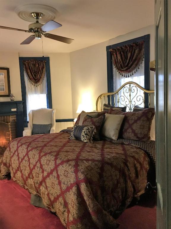 a bedroom with a large bed and two windows at Parsonage Inn Bed and Breakfast in Saint Michaels