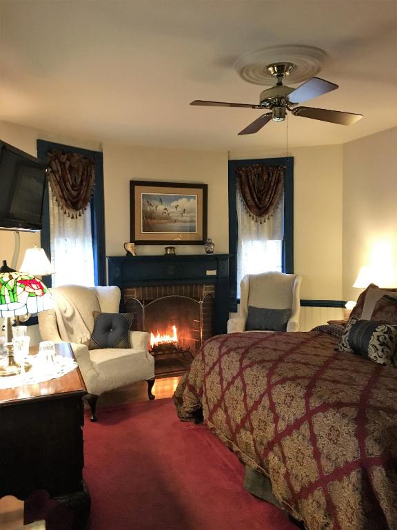 a bedroom with a bed and a fire place at Parsonage Inn Bed and Breakfast in Saint Michaels