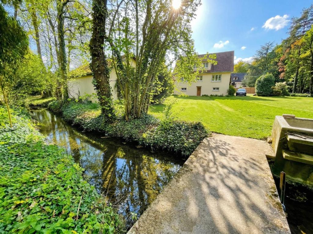 a canal in front of a house with a house at Villa 10-14 guests - 180m2 - private forest - CDG 7min - Disney 20min in Claye-Souilly
