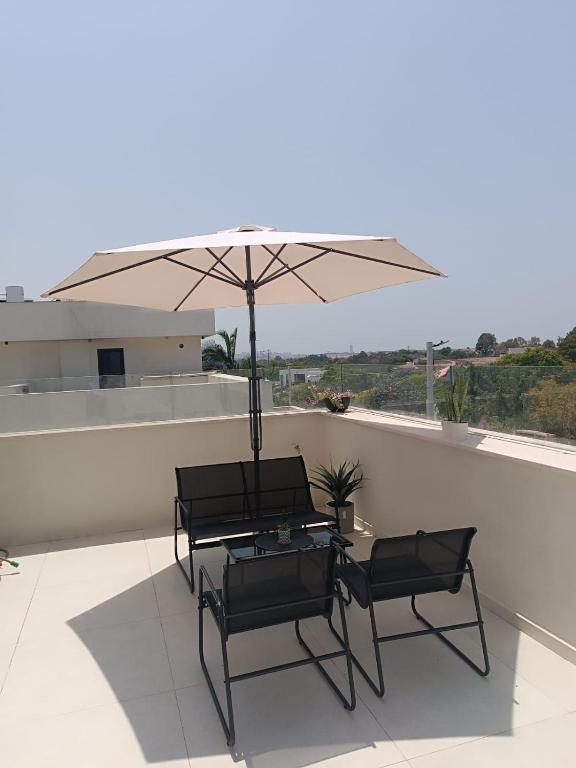 two chairs and a table with an umbrella on a roof at דירת נופש נווה ים in Kefar HaNo‘ar Niẕẕanim
