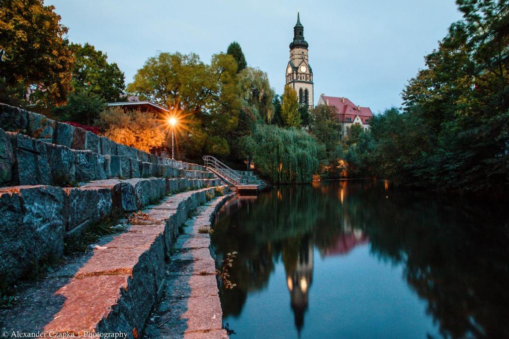 vista su un fiume con torre dell'orologio sullo sfondo di Apartment am Kanal a Lipsia