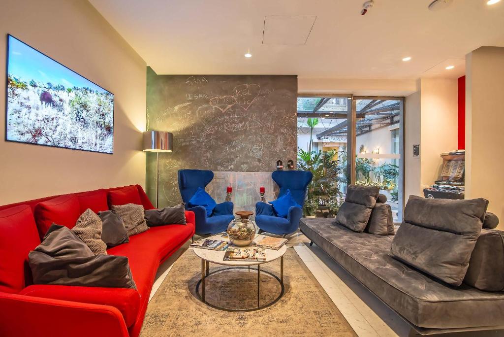 a living room with a red couch and blue chairs at Hotel White in Rome