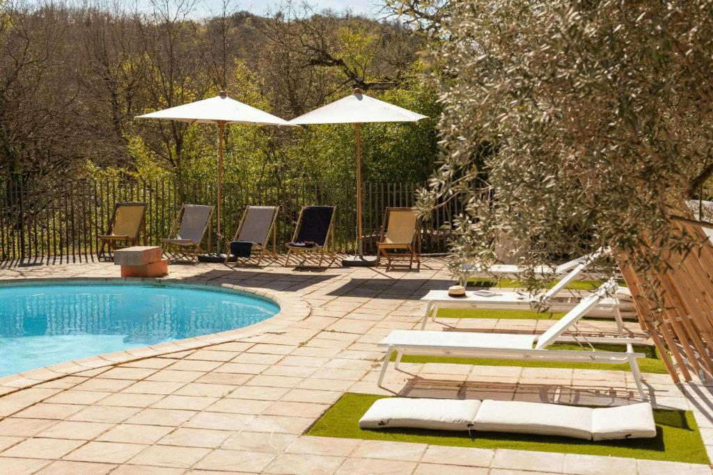 a swimming pool with chairs and umbrellas in a yard at Designer Cabin With Shared Pool In Bras in Bras