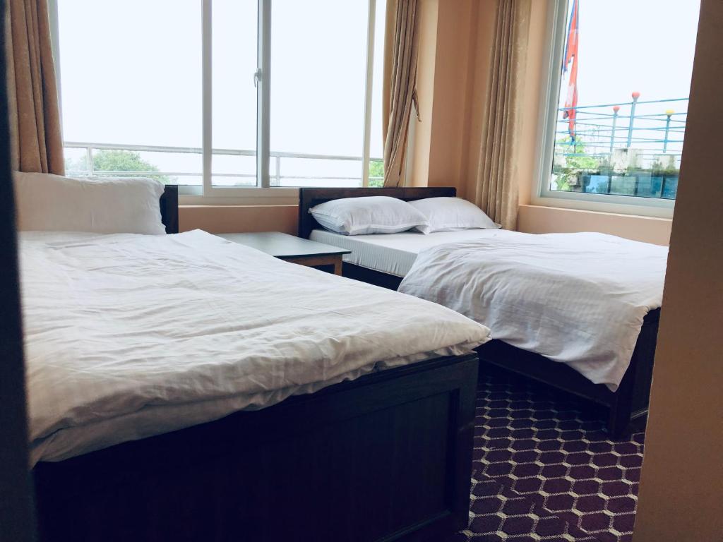 two beds sitting in a room with a window at Hotel New Manakamana in Pāti Bhanjyāng