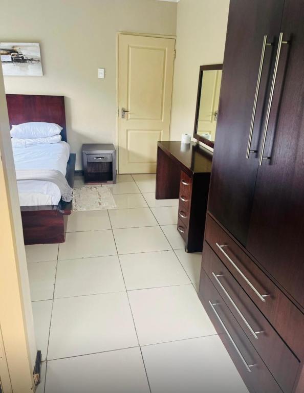 a bedroom with a bed and a dresser and a refrigerator at Folang Resort in Centurion