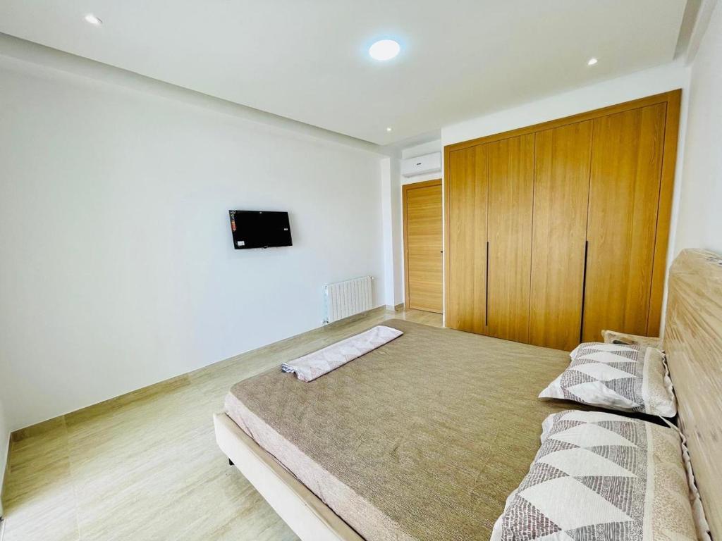 a bedroom with a bed and a tv on the wall at Apparemment s1 vu sur mer et piscine in Zarzis