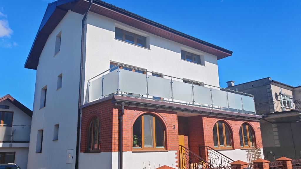 a white building with a balcony on top of it at Willa 2 piętro in Szczecinek