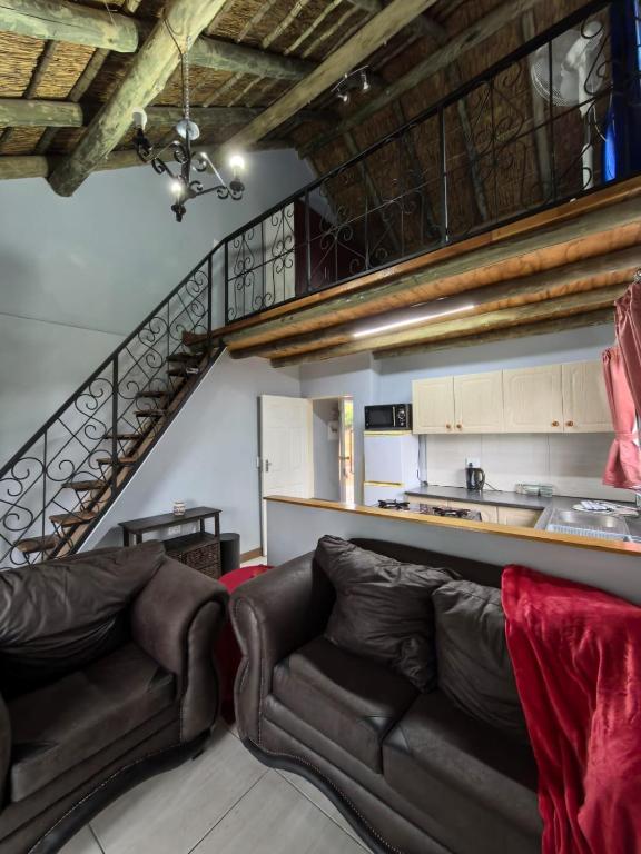 a living room with two leather couches and a staircase at Frangipani guesthouse in Hartbeespoort