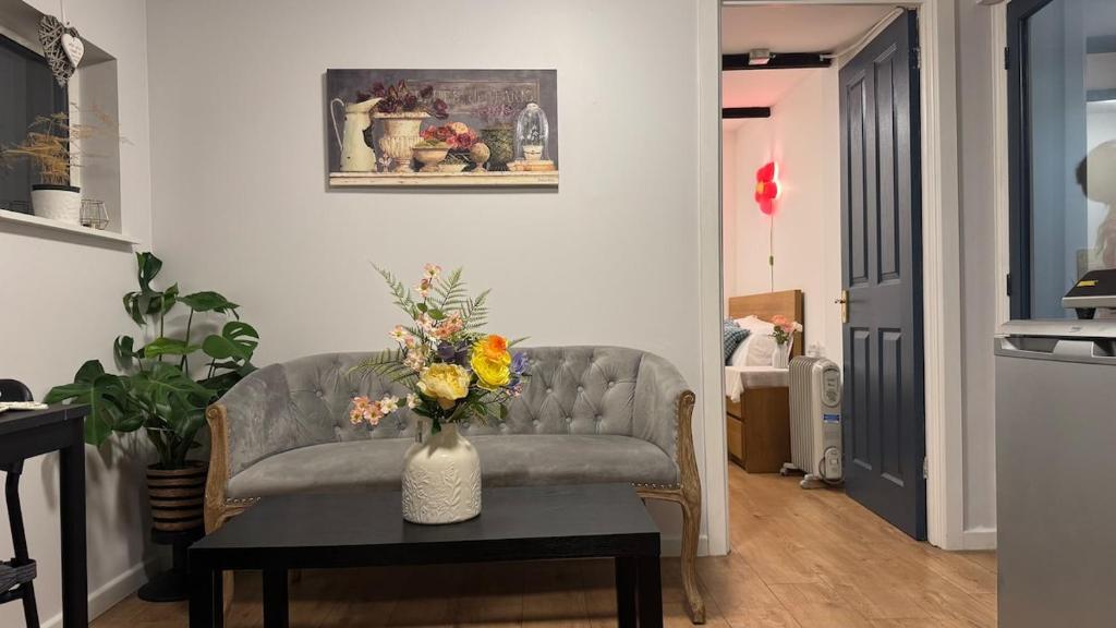 a living room with a couch and a vase with flowers on a table at Hidden Gem in Foots Cray