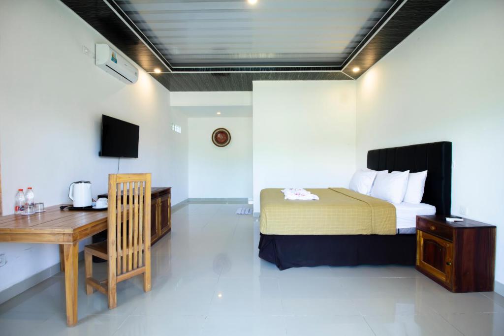 a bedroom with a bed and a desk and a table at Pohon Purba Resort & Restaurant in Pulau Lebur