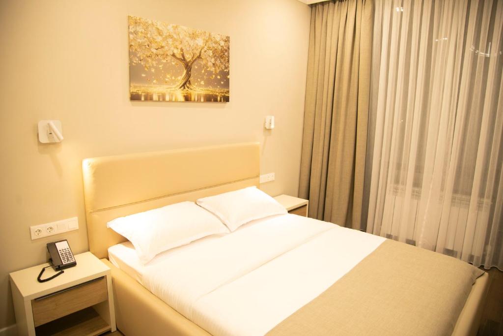a bedroom with a bed and a picture of a tree at Aristocrat Hotel in Kapchagay