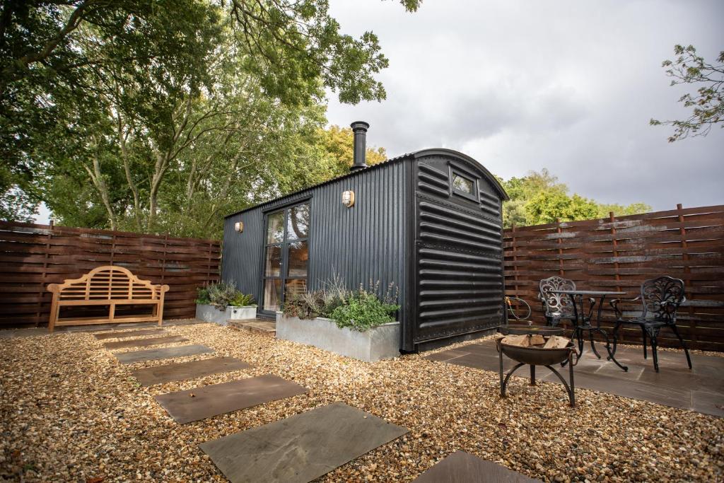 a black tiny house sitting on top of a yard at The Carriage in Kenton