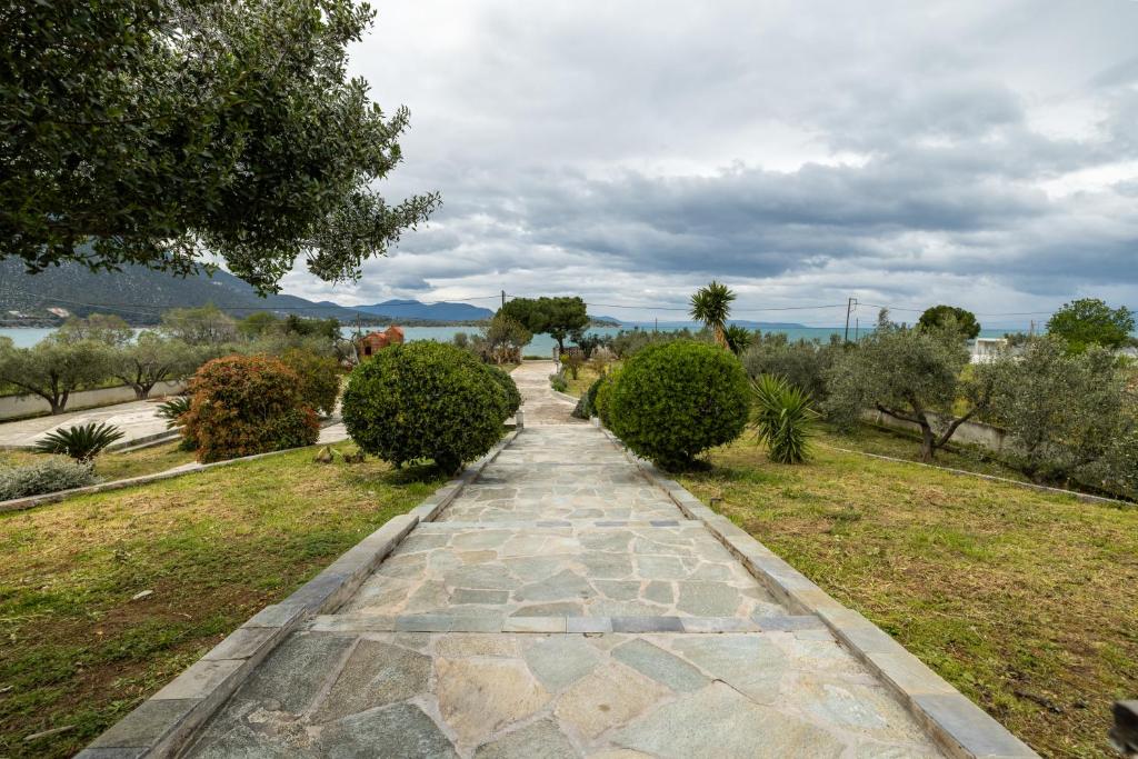 a stone path through a park with bushes and trees at Ioanna Sunset Retreat in Chalkida