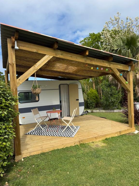 a deck with two chairs and an rv at Caravane Chic et Vintage in Urrugne