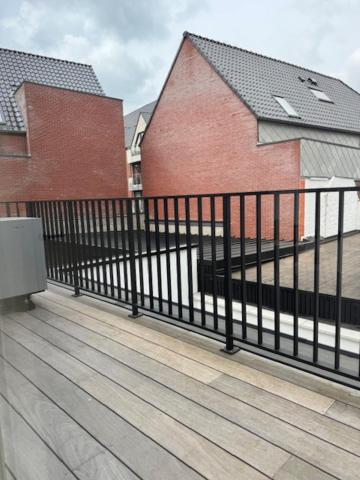 a black fence on a wooden deck with buildings at The Corner-LISETTE in Oedelem