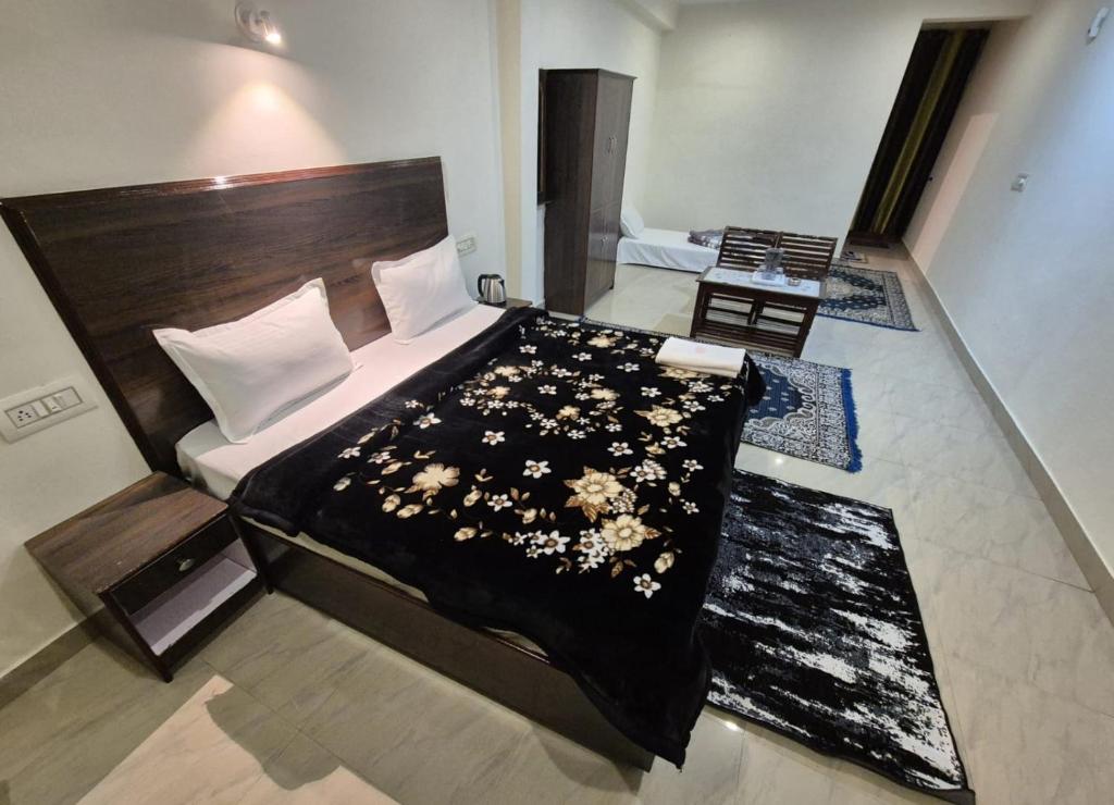 a bedroom with a bed with a black comforter and flowers at Little Tibet Mcleodganj in Dharmsāla