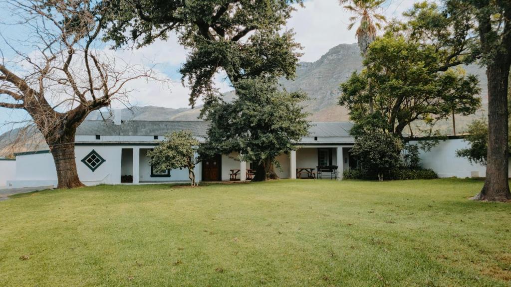 a white house with trees and a yard at Oregon House in Riebeek-Wes