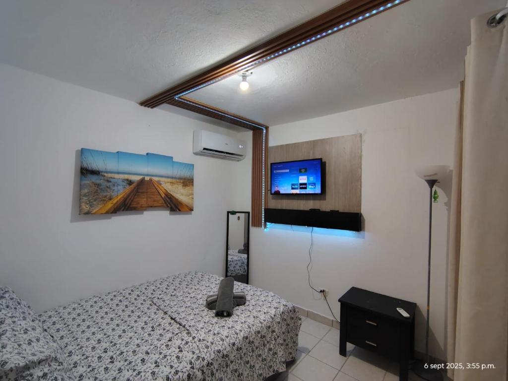 a bedroom with a bed and a tv on the wall at Sleep relax v in Fajardo