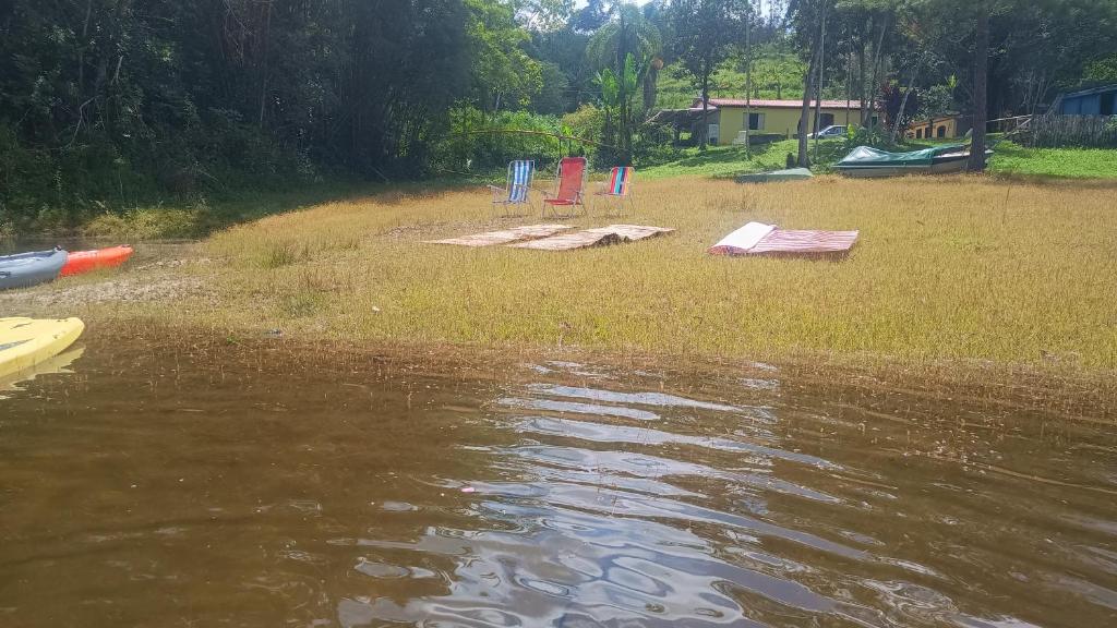 a group of chairs sitting on the shore of a body of water at Chacara desejo do coração dois in Juquitiba
