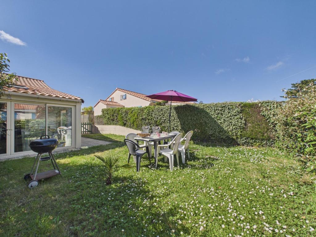 a patio with a table and chairs and an umbrella at Maison avec piscine à 200m de la plage in Saint-Michel-Chef-Chef