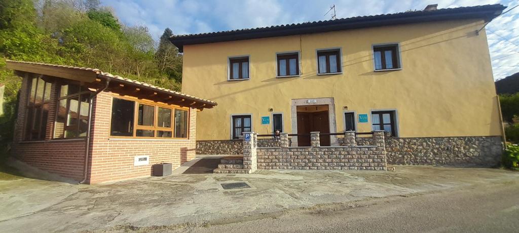 a large yellow house with a porch and a door at Casa La Barria in Nueva de Llanes