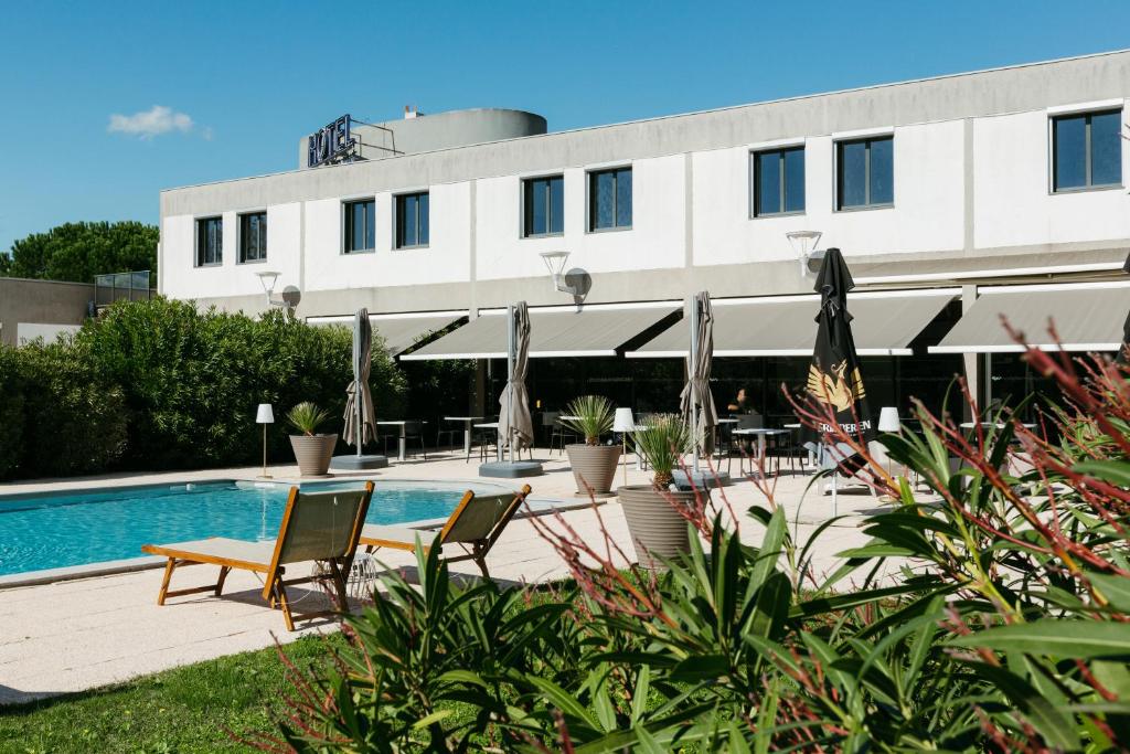 a hotel with a pool and chairs and a building at Sous Les Pins in Étoile-sur-Rhône