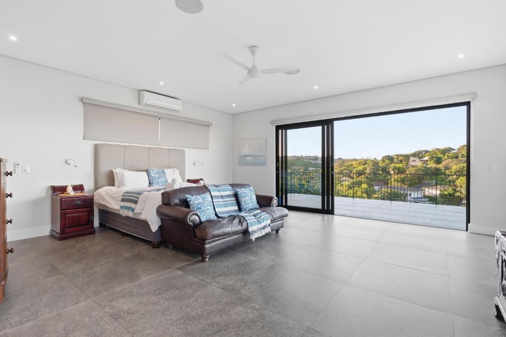 a bedroom with a bed and a couch and a window at Tuna Room in Ballito