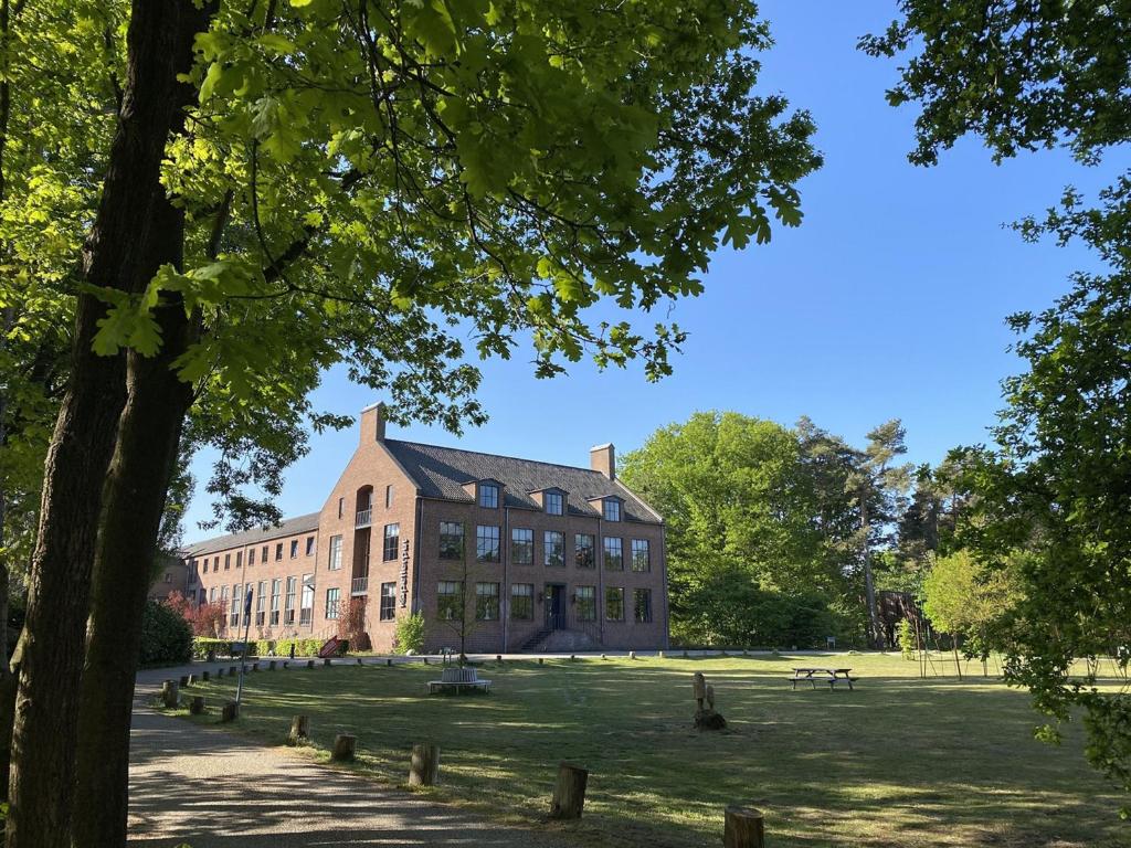 a large brick building on a grass field at Hotel Kapellerput Heeze-Eindhoven in Heeze