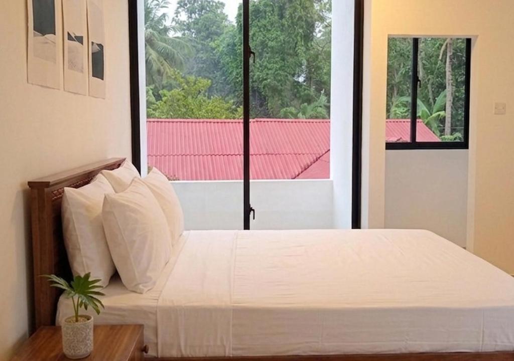a bedroom with a white bed with a window at Eco Bliss Ragama in Ragama