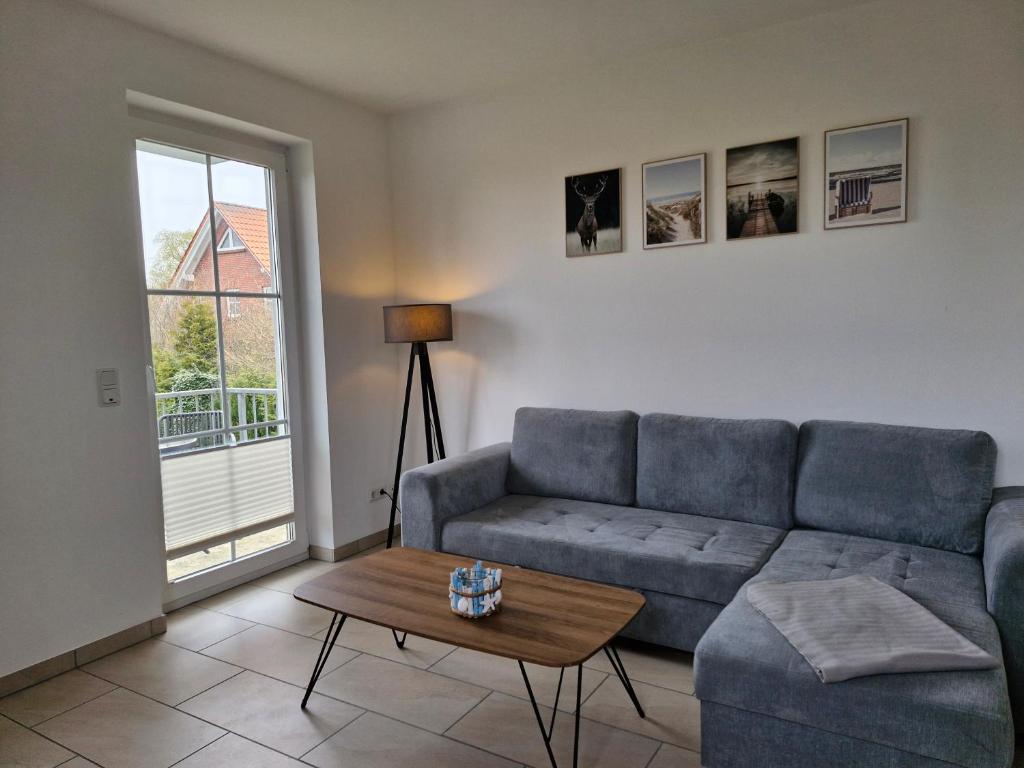 a living room with a blue couch and a table at Apartmenthaus Ostseeluft in Lohme