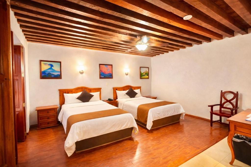 a bedroom with two beds and a wooden ceiling at Hotel Puebla Plaza in Puebla