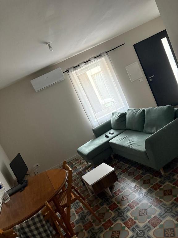 a living room with a green couch and a table at Charmant appartement entre mer et vignes in Portel-des-Corbières