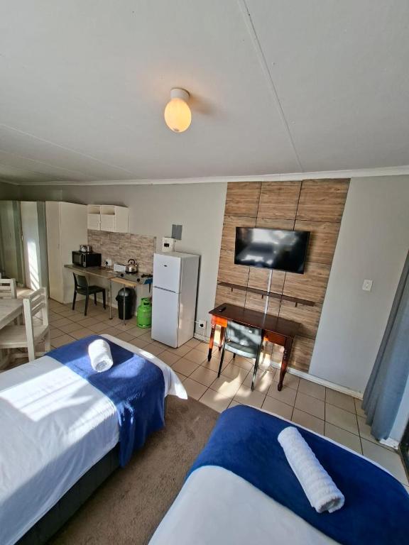 a bedroom with two beds and a flat screen tv at Lullaby Leaf in Lichtenburg