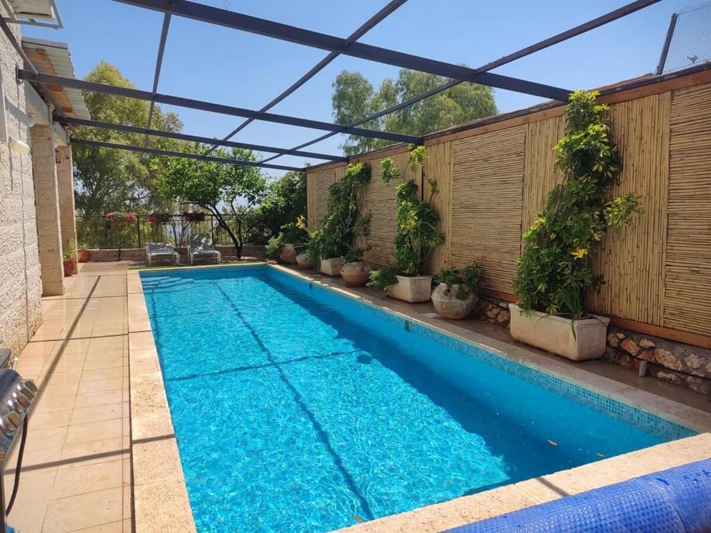a swimming pool in a backyard with a pergola at נופש בפינה in Rosh Pinna