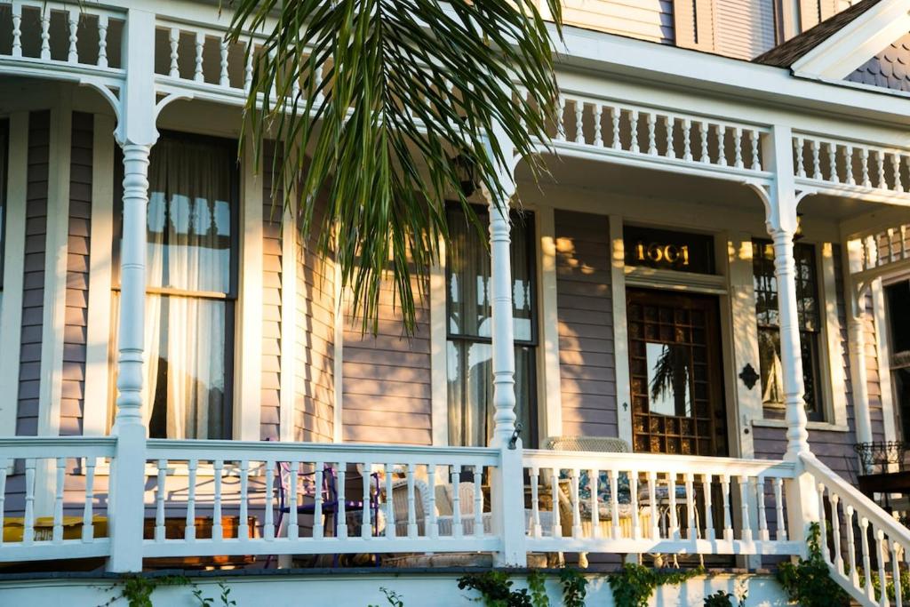 a house with a white porch and a palm tree at Saint Helens House-Hotel Historic District Near Cruise Port in Galveston