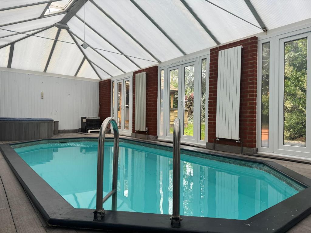 a swimming pool in a house with a roof at Broadway Pool House with Sauna & Jacuzzi in Herne Bay