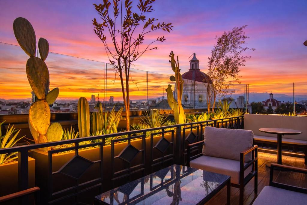 a sunset on a balcony with a chair and cactus at Hotel Tamara in Puebla