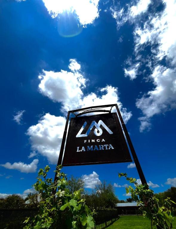 a sign in front of a blue sky with clouds at Finca La Marta - El Cortijo Wine Lodge in Capilla del Monte