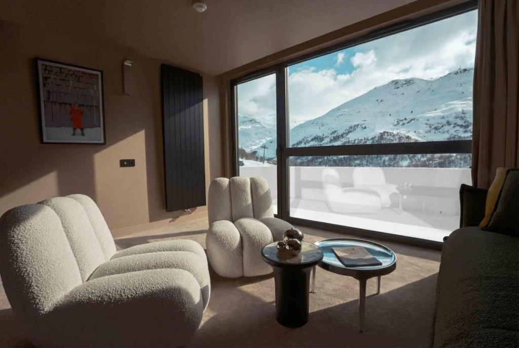a living room with two chairs and a large window at Fahrenheit Seven Les Menuires in Les Menuires
