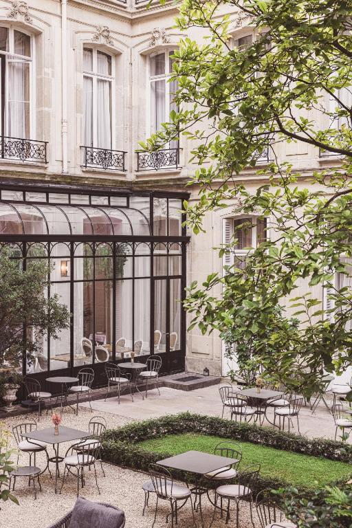 a group of tables and chairs in front of a building at Hôtel Alfred Sommier in Paris