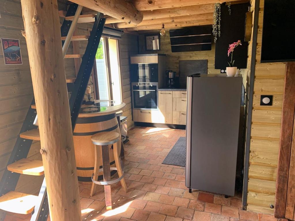 a kitchen with a refrigerator and chairs in a cabin at Le Garage in Lamotte-Beuvron