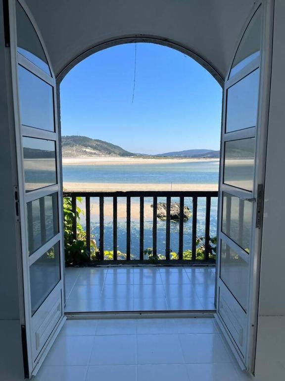 an open door to a balcony with a view of the ocean at Cabanas da Auga in Ures