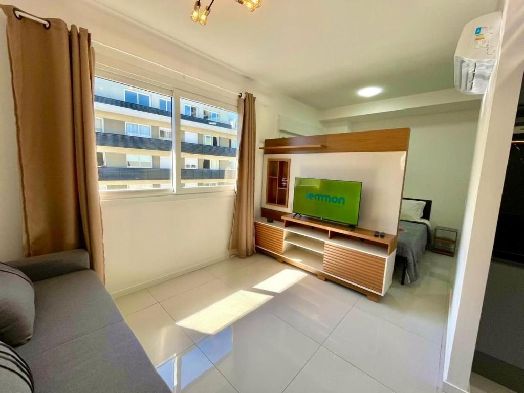 a living room with a tv and a large window at Maxplaza Residential 1209 in Canoas
