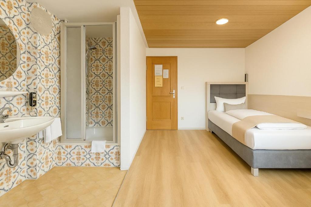 a bedroom with a bed and a sink and a bathroom at Budget Messehotel by Daucher in Nuremberg